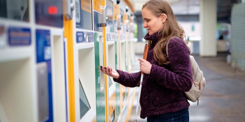 A blind woman uses her smartphone to pay at a ticket terminal.