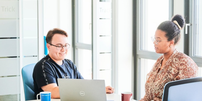 Mitarbeitende mit Notebook im Gespräch