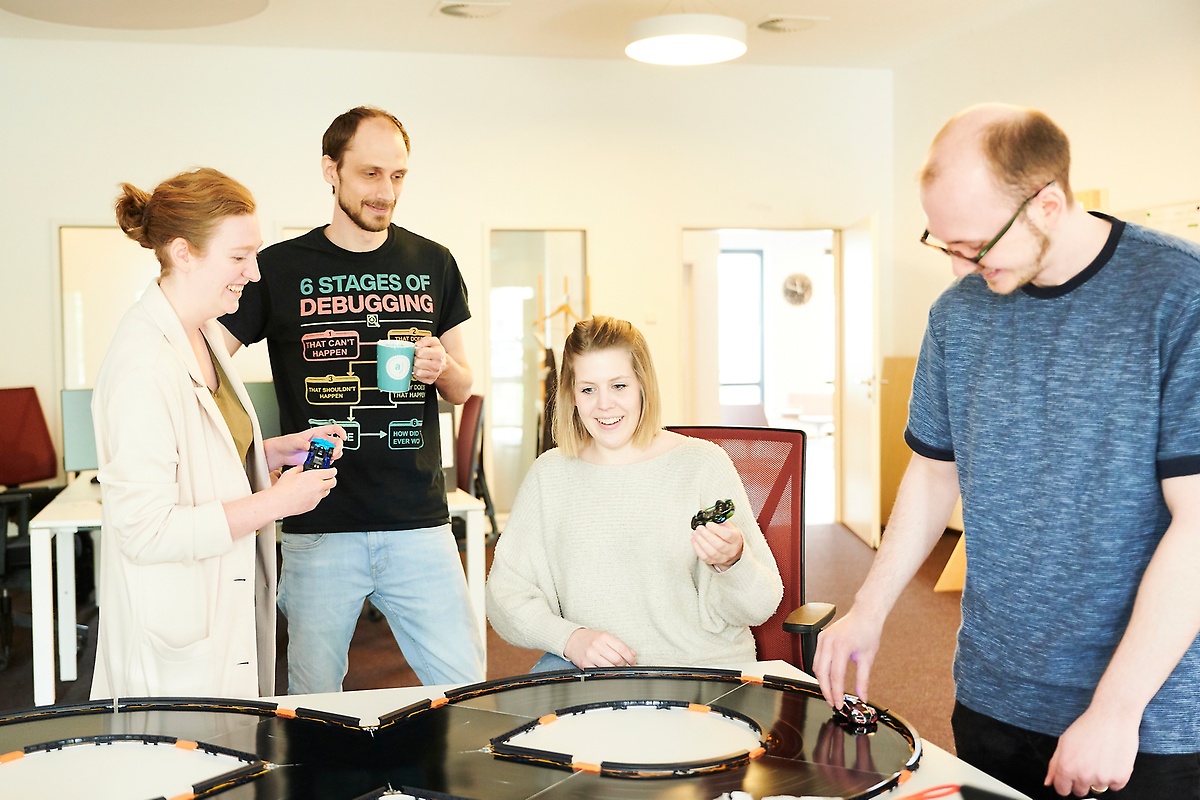 Mitarbeitende im Digital Experience Lab mit der Anki-Overdrive-Bahn