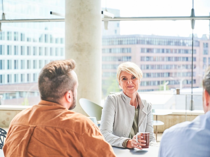 eine Frau an einem Tisch zusammen mit anderen Menschen eine Frau an einem Tisch zusammen mit anderen Menschen