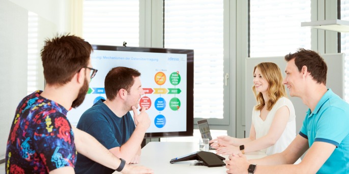 employees sitting together at a table and look at a presentation