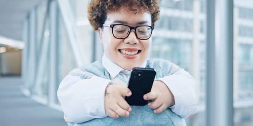 A petite businesswoman smiles as she uses her smartphone while on the move.
