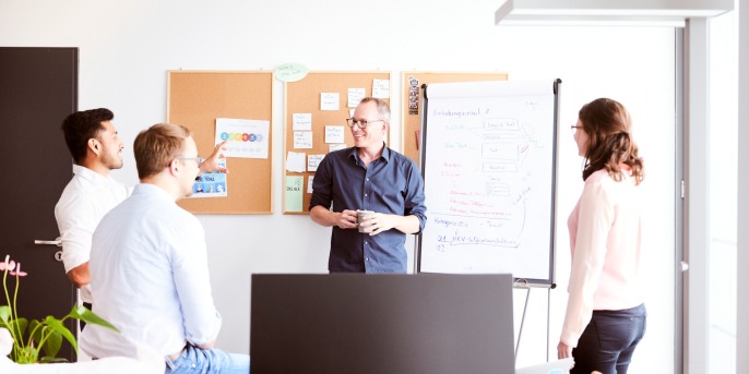 Menschen stehen im Büro vor einer Pinnwand