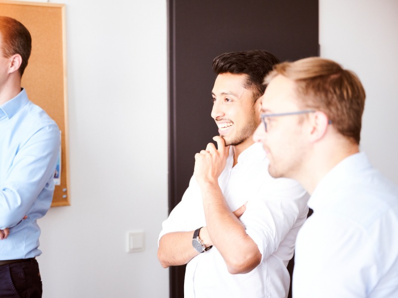 three men stand together and talk