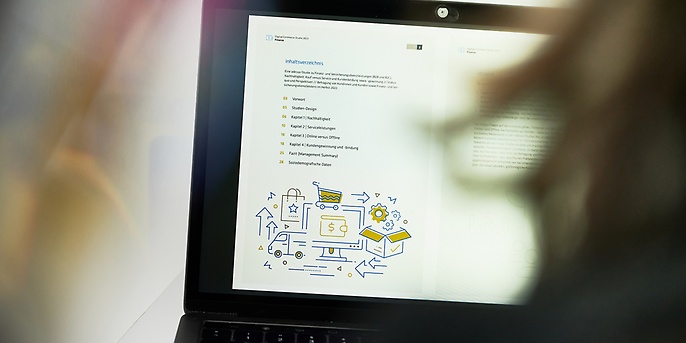 Person die vor einem Notebook sitzt und die adesso Digital Commerce Studie Finance liest