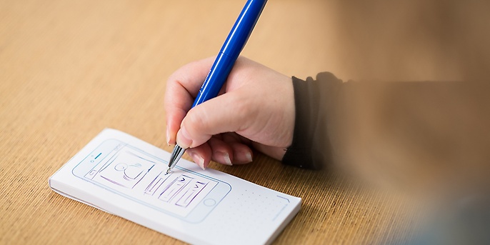 Person zeichnet ein SmartPhone auf ein Blatt Papier