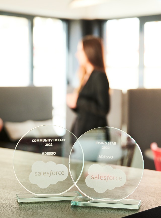Salesforce Award stehen auf einem Tisch und im Hintergrund stehen zwei Personen
