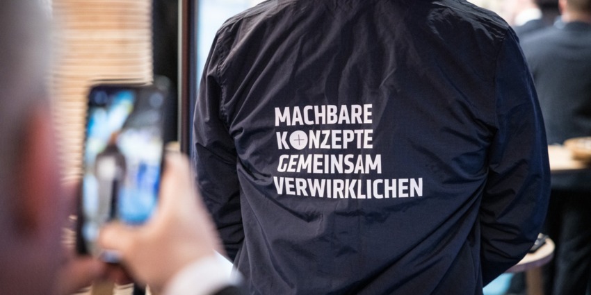 On the back of a shirt it says: Realising feasible concepts together.