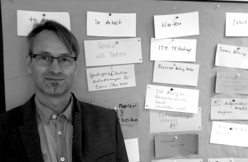 Bild eines Mitarbeiters vor einem Kanban Board